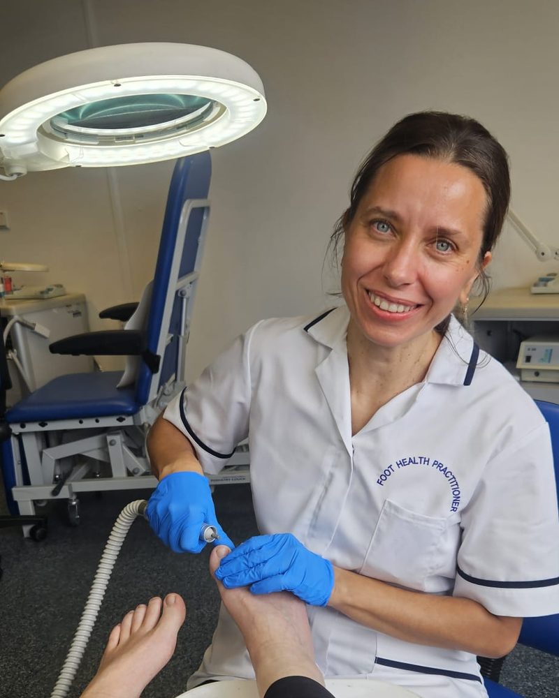 Lina, Foot Health Practitioner, smiling while caring for a client's foot